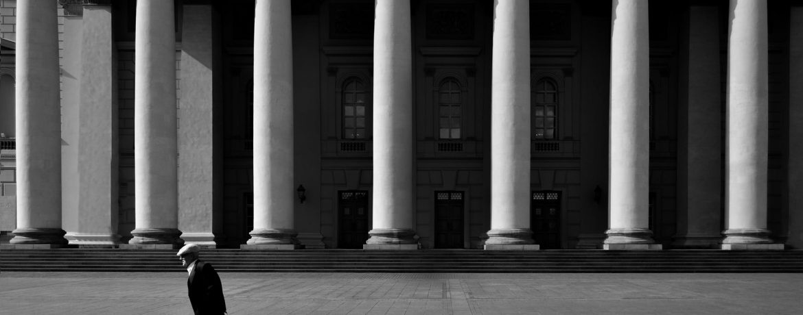 unrecognizable citizen against old urban building with colonnade